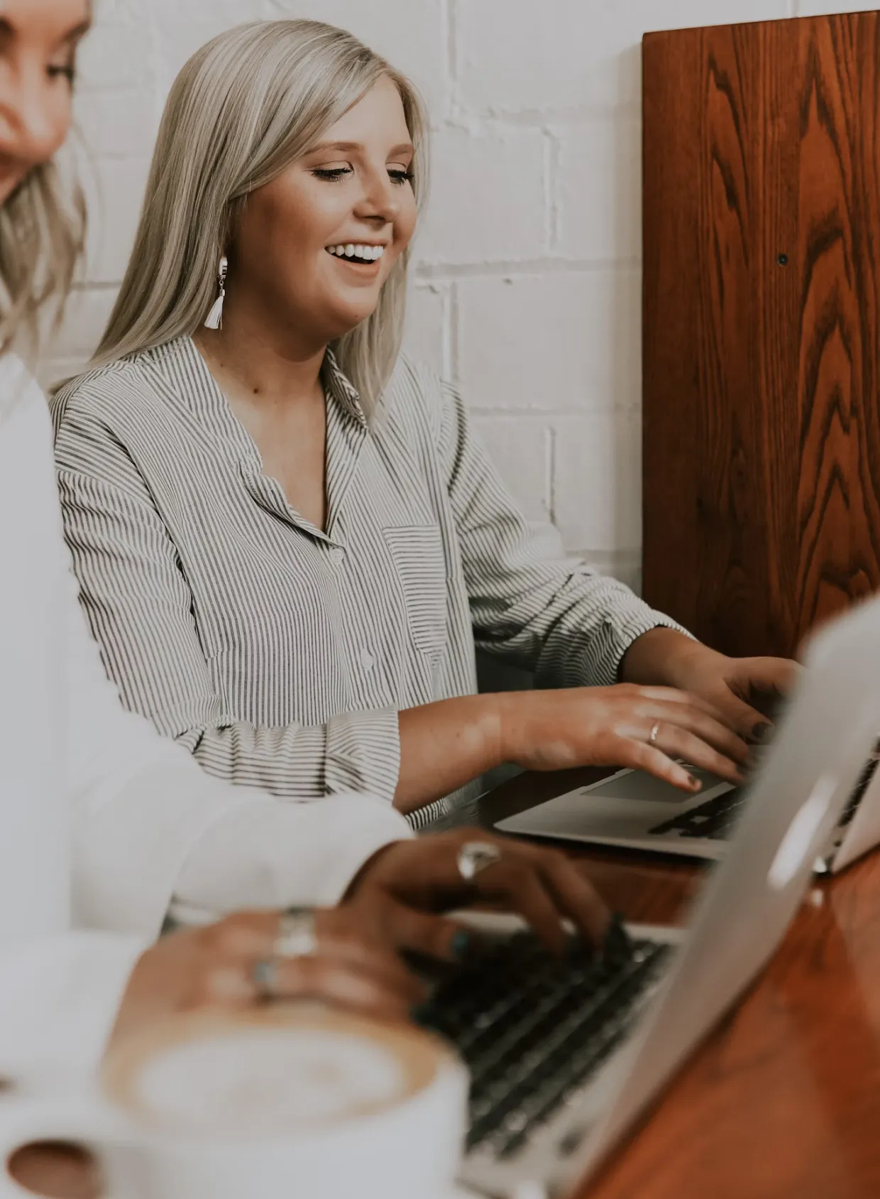 Frau arbeitet lächelnd am Laptop in einem hellen Raum